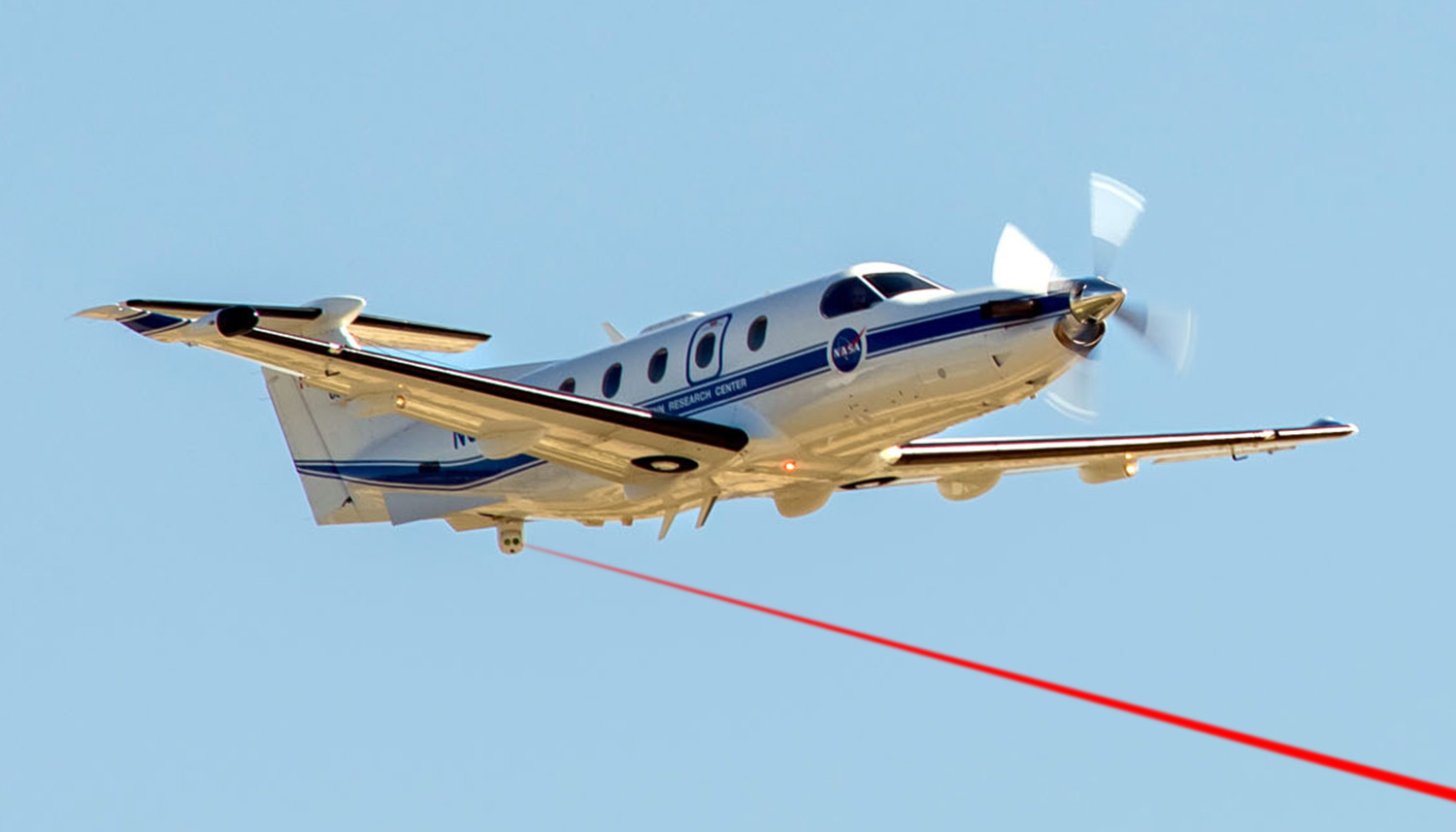NASA's PC-12 aircraft in flight with the Airborne Laser Communication Testbed mounted in the tail cone and a simulated laser beam